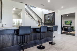 Indoor wet bar with recessed lighting, stairway, light tile patterned floors, and baseboards