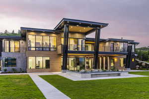 Back of house featuring a balcony, a lawn, and a patio area