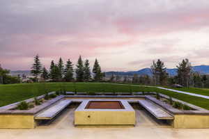 Pool at dusk featuring a mountain view and a yard