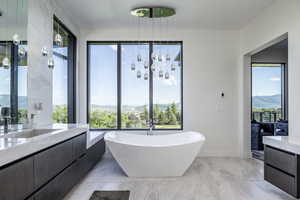 Full bath with a freestanding bath, vanity, baseboards, and a mountain view