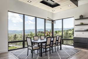 Dining space with a mountain view, hardwood / wood-style floors, wooden ceiling, and a chandelier