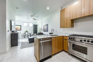 Kitchen with stainless steel appliances, a sink, a peninsula, light countertops, and a ceiling fan