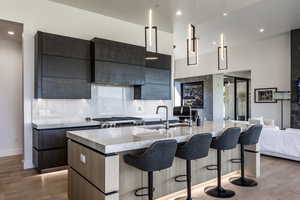 Kitchen with modern cabinets, a sink, light wood-type flooring, a breakfast bar area, and recessed lighting