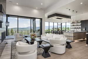 Living room featuring a mountain view, light wood-style flooring, recessed lighting, and a towering ceiling