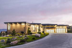 View of front of home with a garage, driveway, stucco siding, and central AC