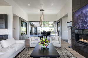 Living area with light wood-style floors, a tile fireplace, recessed lighting, and baseboards