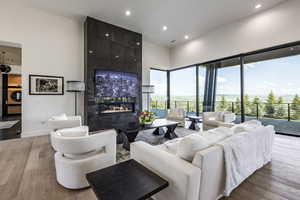 Living area with a tiled fireplace, wood finished floors, recessed lighting, a high ceiling, and baseboards