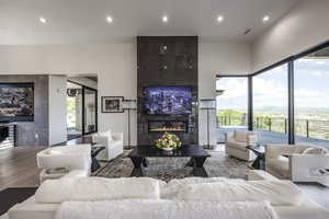 Living room featuring a tiled fireplace, plenty of natural light, wood finished floors, and recessed lighting