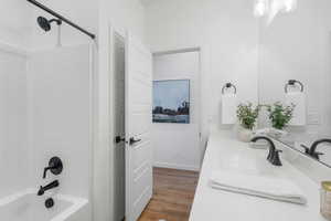 Bathroom with tub / shower combination, vanity, and hardwood / wood-style flooring