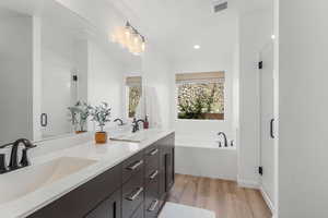 Bathroom featuring separate shower and tub, wood-type flooring, and double sink vanity