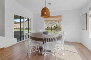 Dining space with light hardwood / wood-style floors and vaulted ceiling