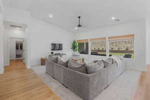 Living room featuring light hardwood / wood-style flooring, lofted ceiling, and ceiling fan