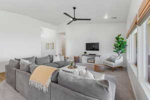 Carpeted living room with ceiling fan and lofted ceiling