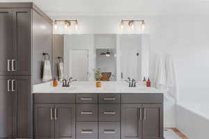 Bathroom featuring a tub to relax in, ceiling fan, and dual bowl vanity