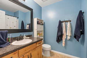 Bathroom with tile patterned flooring, toilet, vanity, and a textured ceiling