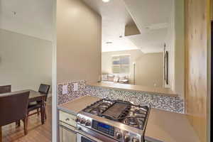 Kitchen featuring stainless steel range with gas stovetop, tasteful backsplash, and light wood-type flooring