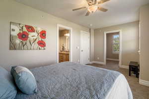 Bedroom with carpet, ensuite bathroom, and ceiling fan