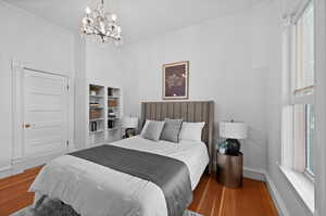 Bedroom with ornamental molding, an inviting chandelier, and hardwood / wood-style flooring