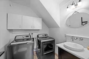 Washroom with tile patterned flooring, washing machine and dryer, and sink