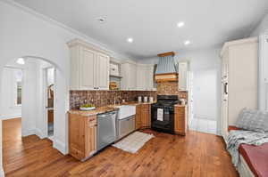 Kitchen featuring tasteful backsplash, sink, dishwasher, hardwood / wood-style flooring, and black range with gas cooktop