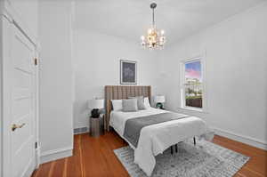 Bedroom with crown molding, hardwood / wood-style floors, and an inviting chandelier