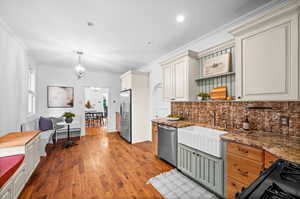 Kitchen featuring tasteful backsplash, stainless steel appliances, decorative light fixtures, hardwood / wood-style flooring, and a notable chandelier