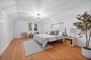 Bedroom featuring vaulted ceiling, light hardwood / wood-style flooring, and a notable chandelier