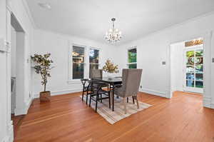 Dining area featuring plenty of natural light, crown molding, a chandelier, and light hardwood / wood-style flooring