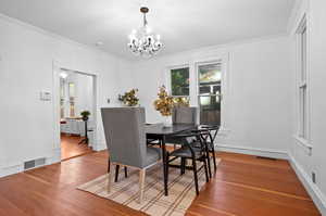 Dining space with an inviting chandelier, crown molding, and hardwood / wood-style floors