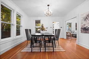 Dining room with an inviting chandelier, hardwood / wood-style flooring, and ornamental molding