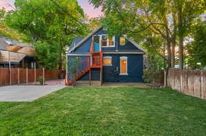 Back house at dusk featuring a yard