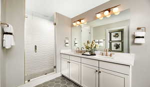 Bathroom featuring LVT flooring, double sink vanity, and a shower with door. Fiberglass insert with glass shower door has been selected for this home.This is a picture of the model home; selections and colors may vary.