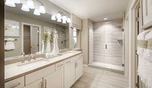 Bathroom featuring a shower with shower door, double vanity, and LVT flooring. Fiberglass insert and glass shower enclosure door has been selected for the primary bathroom.Materials and colors may vary; this pictures is of a model home.