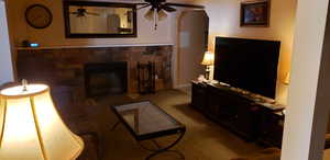 Living room with a fireplace, carpet flooring, and ceiling fan