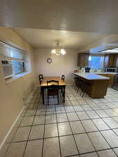 Dining area with sink, a healthy amount of sunlight, light tile patterned floors, and a chandelier