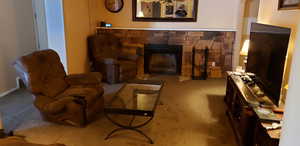 Living room featuring carpet and a stone fireplace