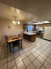 Tiled dining area featuring sink, a textured ceiling, and a chandelier