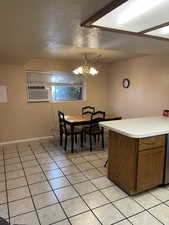 Dining area with light tile patterned flooring, an inviting chandelier, a textured ceiling, and cooling unit