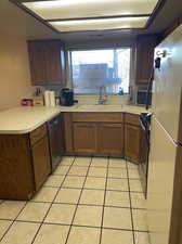 Kitchen with dishwasher, white refrigerator, sink, and plenty of natural light