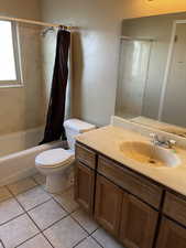 Full bathroom featuring shower / bath combo with shower curtain, tile patterned floors, toilet, and vanity