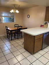 Kitchen with a chandelier, light tile patterned floors, and stainless steel dishwasher