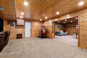 Carpeted living room featuring wood walls and wooden ceiling