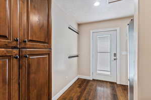 Doorway featuring dark hardwood / wood-style flooring and a textured ceiling