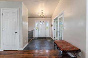 Tiled entrance foyer featuring vaulted ceiling, a textured ceiling, and a notable chandelier