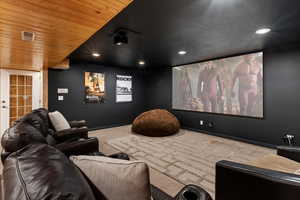 Carpeted cinema room featuring wooden ceiling