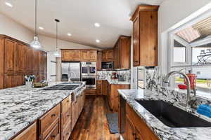 Kitchen featuring backsplash, dark wood-type flooring, stainless steel appliances, hanging light fixtures, and sink