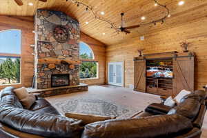 Living room featuring carpet floors, wood ceiling, a fireplace, a barn door, and ceiling fan