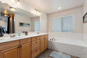 Bathroom featuring dual vanity, tile patterned floors, a washtub, and plenty of natural light