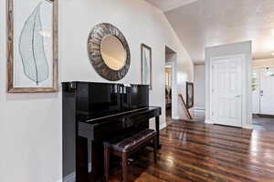 Miscellaneous room with dark wood-type flooring and vaulted ceiling