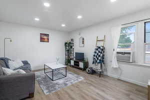 Living room with cooling unit and light hardwood / wood-style flooring